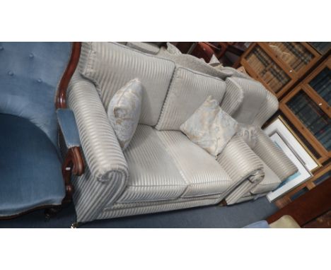 A contemporary two seater sofa upholstered in cream and gold material on mahogany feet, with large brass castors, with matchi