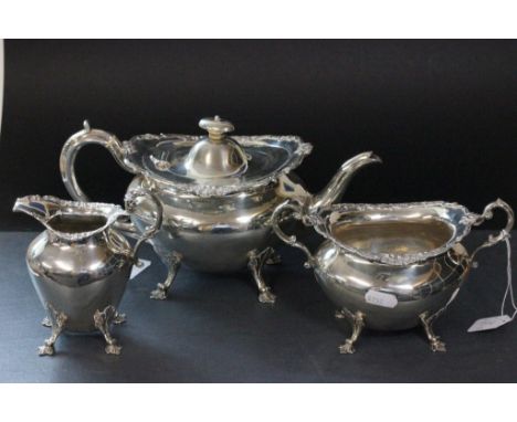 A silver three piece tea service comprising teapot, sugar bowl and milk, with rim of each piece decorated with a flower and p