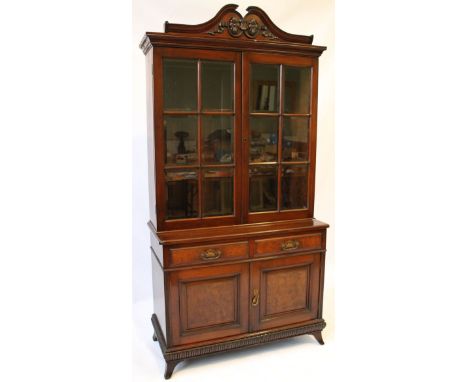 An elegant Edwardian walnut bookcase 
The foliate carved scrolling pediment above two bevelled glazed panel doors, the base s