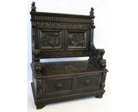 A Victorian carved oak settle
The chisel carved top rail featuring two carved portrait busts, above the back panel carved wit