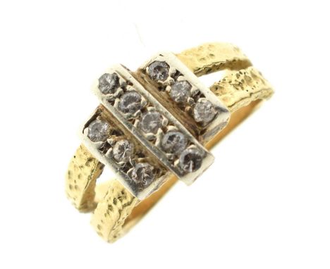Modernist diamond ring, the eleven brilliant cuts set into three panels, the split shoulders having a hammered effect finish,