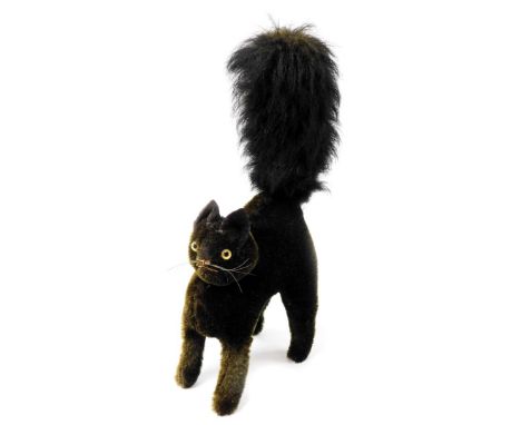 An early 20thC black mohair startled tom cat, in the manner of Steiff having glass eyes and red stitched nose and mouth, 35cm