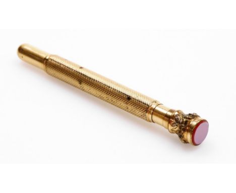 An early 20thC gilt metal pencil case, with engine turned body decoration and foliate scroll top with agate set top, unmarked