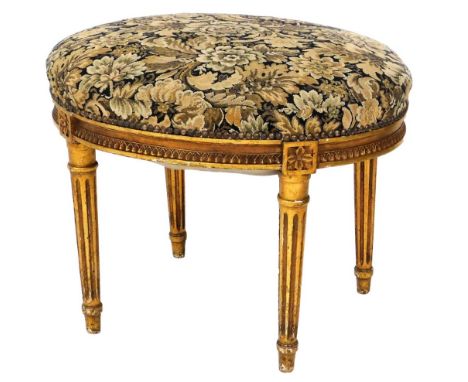 A 19thC oval giltwood stool, with overstuffed and sprung tapestry seat, and reeded taper legs, 50cm high, 64cm wide, 50cm dee