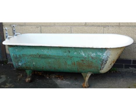 A Victorian cast iron and enamel bath, of bull nose shape, on heavy cast hairy paw feet, with two taps and plug, 160cm long.
