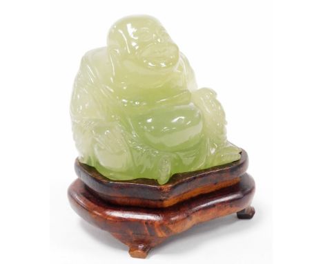 A 20thC Chinese jade coloured glass figure of a Buddha, on a hardwood stand, 10cm high overall.