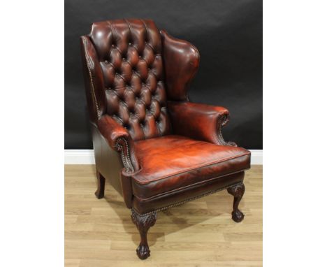 A George II style 'Chesterfield' wingback armchair, stuffed over upholstery, deep-button back, squab cushion, ball and claw f