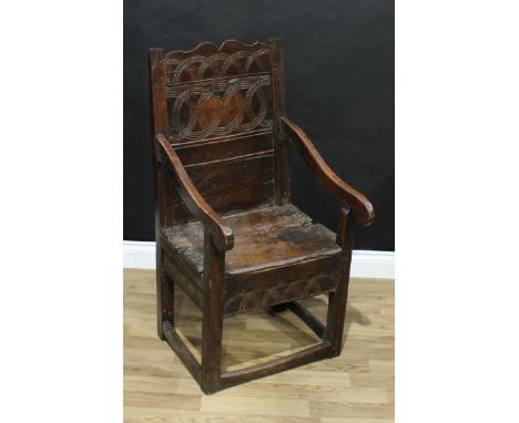 An 18th century oak Wainscot armchair, shaped back incise carved with intersecting compass-drawn lunettes and circles, downsw