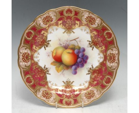 A Royal Worcester shaped circular plate, painted by Albert Shuck, signed, with apples and grapes, within fancy gilt cartouche