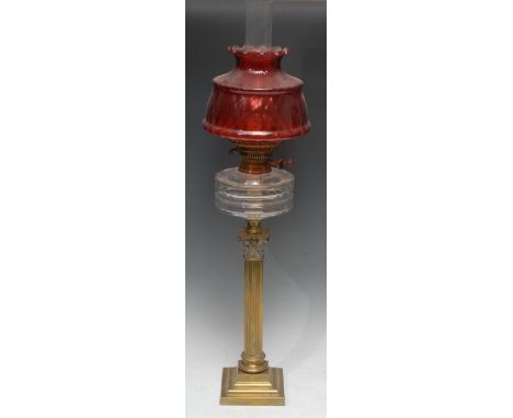 An early 20th century oil lamp, brass Corinthian column, clear glass reservoir, cranberry glass shade, 80cm high, c.1910 