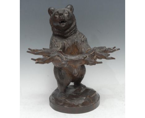 A 19th century Black Forest bear pipe holder, he stands naturalistically carved, holding a branch, 31cm high, c.1880 