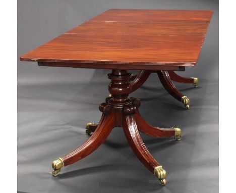 A Regency mahogany twin pillar dining table, rounded rectangular top with reeded edge, additional leaf, turned pillars, hippe