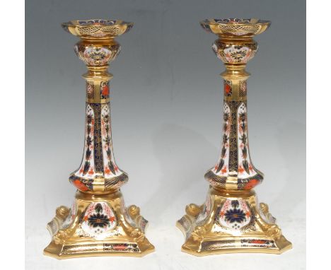 A pair of Royal Crown Derby 1128 pattern Castleton candlestick, outswept square base with dolphins to angles, 26.5cm to fitti