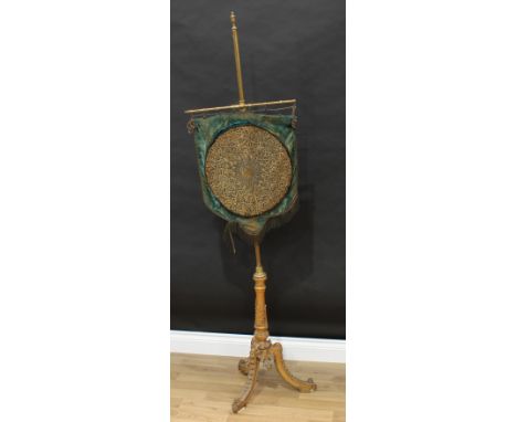 A 19th century giltwood and brass tripod pole screen, by W.Homann and Son, London W., label, urnular finial, the shield shape