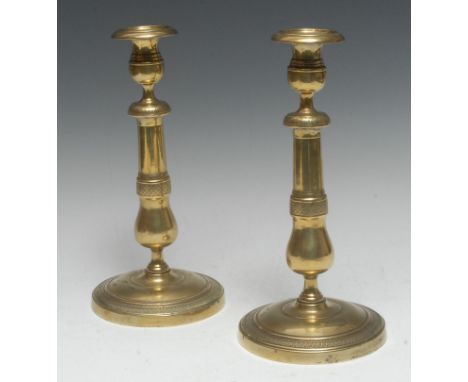 A pair of large French Empire brass table candlesticks, campana sconces with detachable nozzles, baluster pillars, engine tur