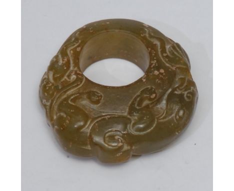 A carved jade ring, the single piece of polished jade, exterior carved as a stalking mythical beast coiled around the circula
