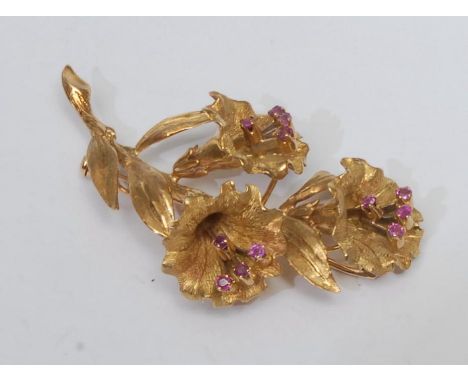 A mid 20th century floral spray brooch, triple trumpet spray each inset with four pinky red ruby tipped stamen's, 18ct gold f