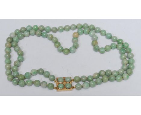 A pale jade green two strand bead necklace, two uniform strands of multi tone green beads, united by a four stone cabochon in