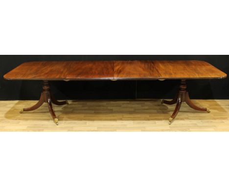 A Regency style mahogany rounded rectangular twin-pillar dining table, moulded top, turned baluster columns, sabre legs, bras