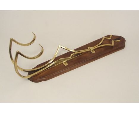 ART NOUVEAU COAT HOOK.
A French Art Nouveau brass coat hook, length 52cm, mounted on a wooden panel.
