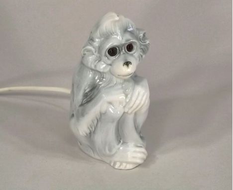 NIGHT LIGHT.
A continental porcelain, glass eyed monkey electric night light/pastille burner. 
Height 29cm.