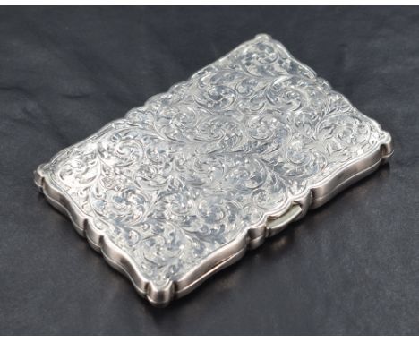 A late Victorian silver visiting card case, of shaped and hinged rectangular form with engraved foliate decoration around a c