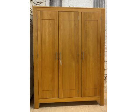 A contemporary light hardwood triple wardrobe, the interior fitted with shelves and for hanging, raised on stile supports, H1