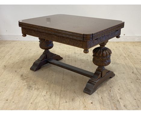 A carved oak duo draw leaf extending dining table, the frieze carved with vining leaves and berries, raised on acanthus carve