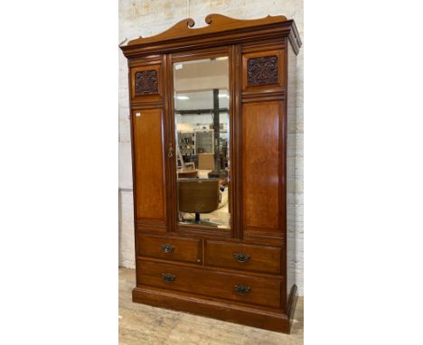 An Edwardian mahogany wardrobe, the swan neck pediment over bevel glazed mirror door opening to an interior fitted for hangin