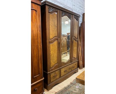 A late Victorian walnut triple wardrobe, the centre bevelled mirror door flanked by two figured walnut panelled doors, all op