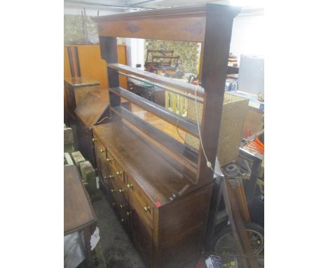 A George III oak dresser, raised and open plate rack fitted with three shelves, cushion moulded cornice, three long drawers a
