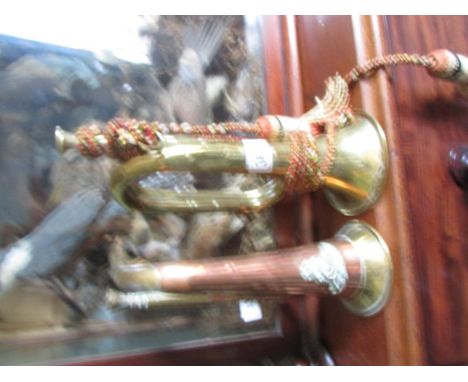 A brass bugle together with a copper and brass bugle.