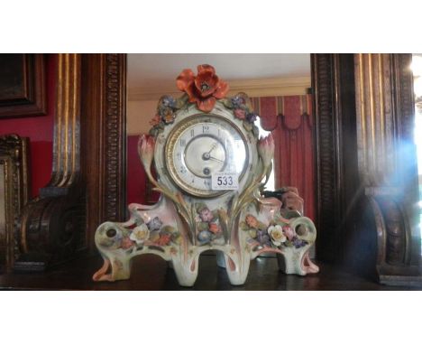 A ceramic mantel clock decorated with flowers.