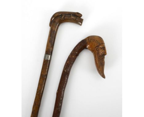 2 geschnitzte Spazierstöcke. Um 1900.             L 80 bzw. 91 cm.             Aus einem Stück gefertigter Stock mit freundli
