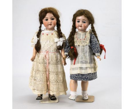 2 Mädchenpuppen mit geflochtenen Zöpfen. Beide gemarkt. Um 1900 bis 1935.Biskuitporzellan, Masse. L max. 60 cm. Beide mit Kur