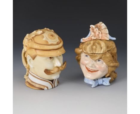2 Gesichtskrüge. Mädchen Schierholz gemarkt. 2. Hälfte 19. Jh.             Porzellan farbig bemalt. H maximal 16,5 cm.       