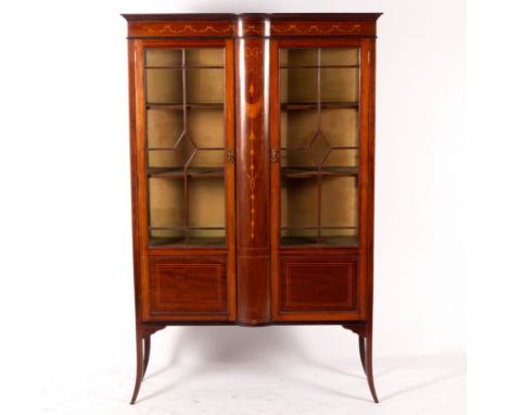 An Edwardian mahogany and inlaid display cabinet with glazed panel doors flanked by an inlaid central bowfront panel, on spla