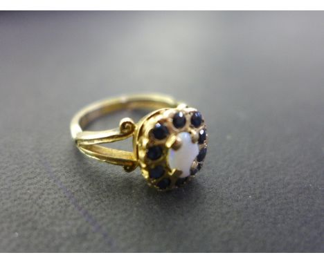 A pretty 9ct gold opal and sapphire ring in the Georgian style, centre opal set with ten small sapphires - Ring size N - Weig