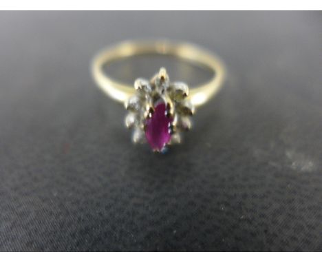 A 9ct yellow gold cluster ring the central oval cut ruby surrounded by ten small diamonds - ring size P - approx weight 1.4 g