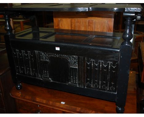 An early 20th century ebonised oak linenfold three panelled monks bench, having typical fold-over top and hinged boxseat base