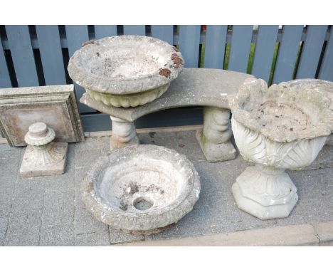 A reconstituted stone garden bench seat, of curved form; together with two pedestal planters; a pair of circular planter tops