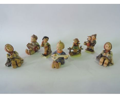 A collection of seven Hummel figures of children including a child playing a lute, a child playing an accordion, two little g