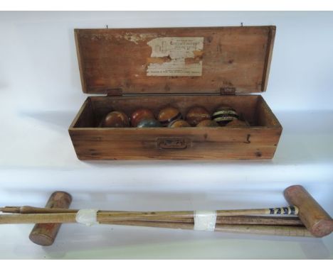 A pine box containing a vintage croquet set comprising nine timber balls with banded detail in shades of blue, white and red 