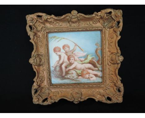 A ceramic tile with painted decoration of four cherubs riding on dolphins, in a gilt moulded and pierced frame with Frost & R