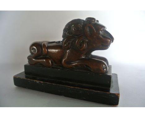 An unusual carved timber model of a stylised lion in seated pose facing forward with tail meeting its back, upon a two divisi