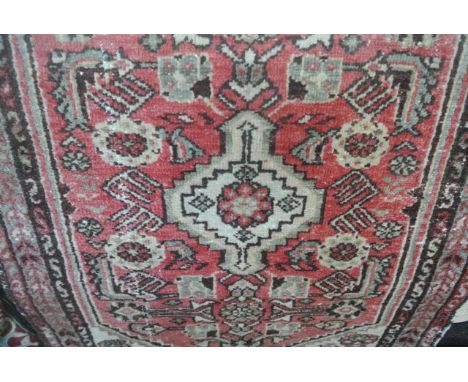 A small wool carpet in the Persian style with red ground field, geometric detail, set within running borders, 115 x 80 cm