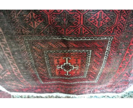 A Persian style red wool carpet with geometric detail upon a red field, within further running borders, 200 x 105 cm