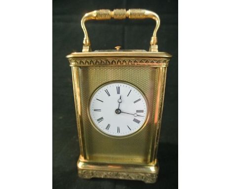 A French brass carriage clock with chased case, the circular enamel dial within an engine turned mask, with 8 day striking mo