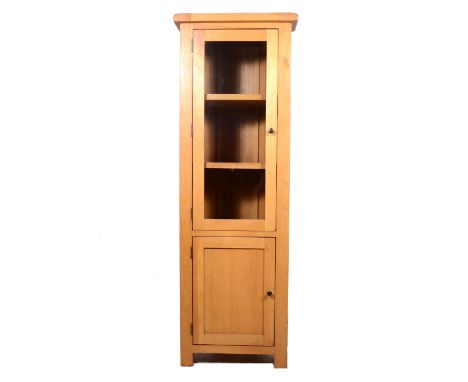 Contemporary light oak freestanding corner cupboard, glazed door over a panelled door, width 66cm, height 189cm.