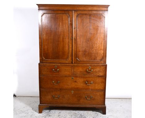 Late Georgian oak linen Press, moulded cornice, plain frieze, the upper section with doors enclosing slides, the base with tw